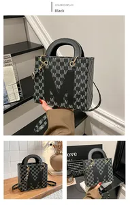 Close-up of black tote bag with M-letter pattern, circular handle and gold hardware