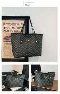 Detail of black monogram tote bag with gold bow ornament and slim shoulder straps