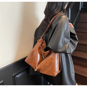 Close-up of vintage brown leather hobo bag showing texture and bronze metal buckle