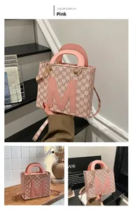 Detail of pink retro handbag with coffee M-letter pattern and golden metal buckle