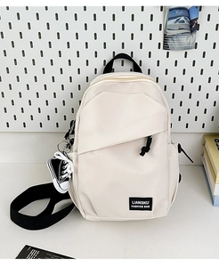 Detail of minimalist beige canvas backpack featuring a fashion tag and mini shoe charm