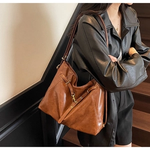 Detail of vintage brown leather tote bag with matte finish and bronze metal buckle detail