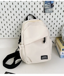 Detail of off-white nylon backpack showing brand label and front diagonal zipper pocket