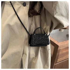 Dettaglio di una mini borsa a tracolla leopardata indossata su un trench kaki classico