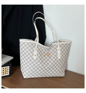 Détail d'un grand sac cabas avec imprimé lettre M grise et ornement en métal à nœud doré