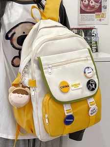 Close-up of yellow and white school backpack with cute plush charm and fashion badges