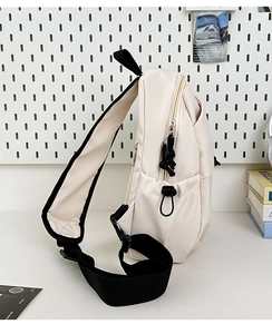 Side view of cream nylon crossbody bag showing the zipper and adjustable strap details