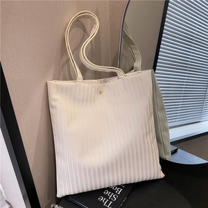 Minimalist beige pleated tote bag with vertical texture and gold rivet accent