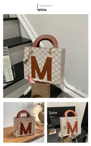 Close-up of retro white canvas tote bag with brown leather M patch and floral textures