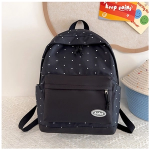 Detailed view of black polka dot canvas backpack with front zipper pocket and logo