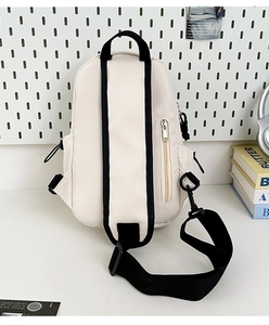 Detail view of cream nylon crossbody bag with black zippers and adjustable wide strap