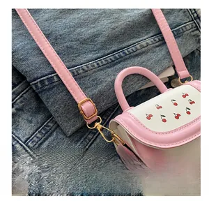 Close-up of golden metal hooks and pink adjustable shoulder strap on cherry crossbody bag