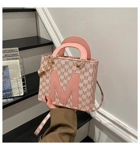 Detail of pink monogram tote bag with large M letter applique and gold metal hardware