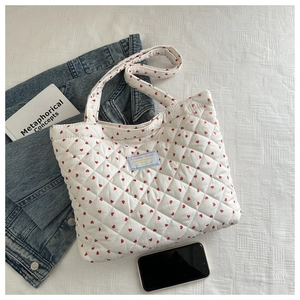 Gros plan d'un sac cabas matelassé blanc avec motifs de cœurs rouges et étiquette