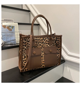 Detail of leopard print tote bag featuring two front pockets and brown leather straps