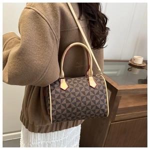 Sac Boston vintage marron avec motifs géométriques porté en bandoulière élégante