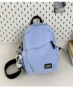 Close-up of light blue nylon sling bag featuring side mini shoe charm and brand logo