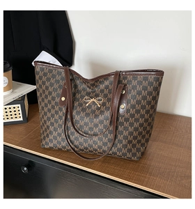 Détails de l'ornement nœud doré et du motif monogramme M sur le sac cabas marron