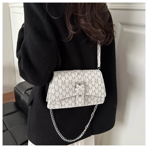 Detail of a beige flap bag with M-letter print and silver chain strap on a black coat