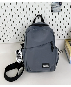 Detail of grey nylon crossbody bag with zipper pocket and stylish sneaker keychain