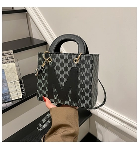 Detail of grey patterned shoulder bag with leather M patch and metal hardware hooks