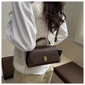 Close-up of retro brown leather crossbody bag with vintage gold clasp on model