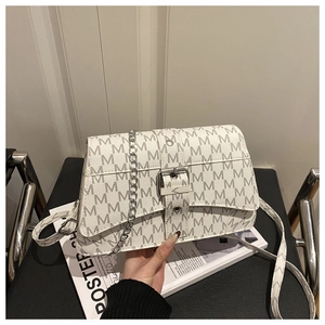 Detail of white monogram handbag featuring silver buckle and decorative metal chain