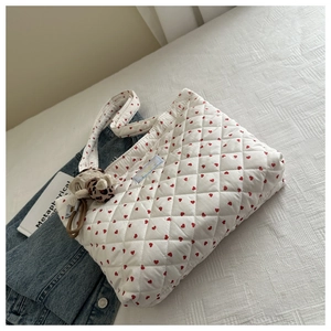 Détail d'un cabas blanc matelassé avec motif cœur rouge et pendentif chat léopard