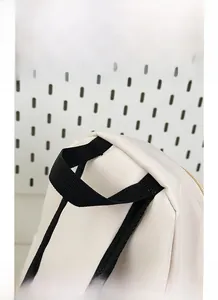Detail of cream crossbody bag showing black nylon handle with reinforced stitching and metal zipper