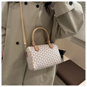 Détail d'un sac Boston à motif géométrique avec poignées marron porté par un mannequin