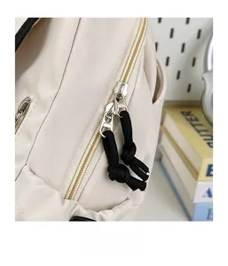 Detail of smooth two-way zippers with black cord pulls on a beige nylon crossbody bag
