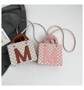 Close-up of retro square bags with M letter prints and detachable patterned shoulder straps