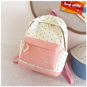 Detailed close-up of cream and pink polka dot backpack with a Lolo fabric brand label