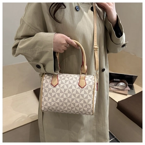 Détail d'un sac Boston à motif géométrique montrant les coutures fines des poignées en cuir