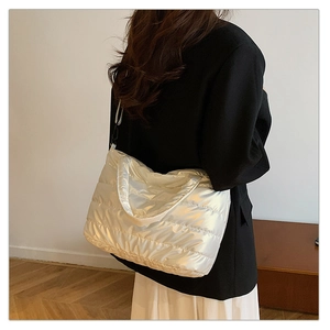 Détail du sac matelassé argenté brillant porté par un mannequin dans un décor minimaliste