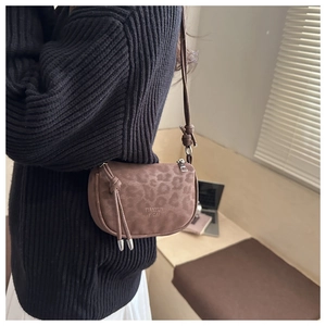 Sacoche marron motif léopard avec franges portée sur un pull en maille noir élégant