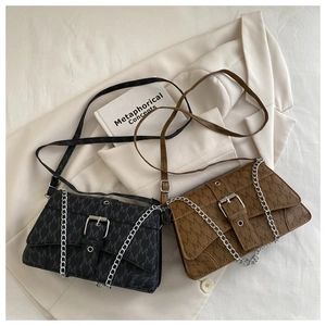 Detail view of retro monogram crossbody bags with metal chains on a stylish blazer