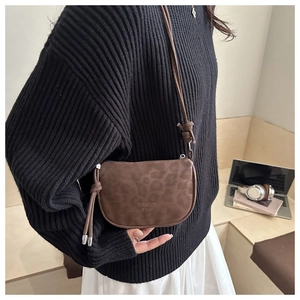 Détail du sac bandoulière vintage léopard avec fermeture à gland et logo de marque