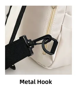Close-up of black rotatable hardware hook and zipper detail on white nylon crossbody bag