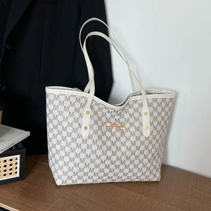 Sac cabas beige vintage avec imprimé lettre M et nœud doré sur un bureau