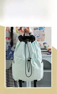 Detail of mint green drawstring backpack showing front open pocket and nylon texture