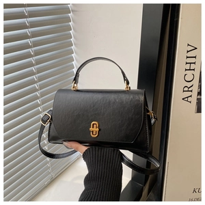 Detail of black crossbody bag with gold rotating clasp and sleek vintage leather texture
