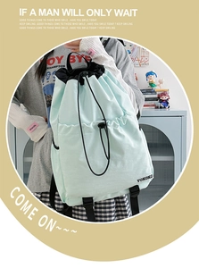 Detail view of the mint green drawstring backpack with multi-pocket design and nylon texture