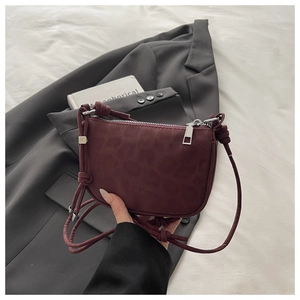 Vue détaillée du motif léopard discret sur un sac à main demi-lune bordeaux