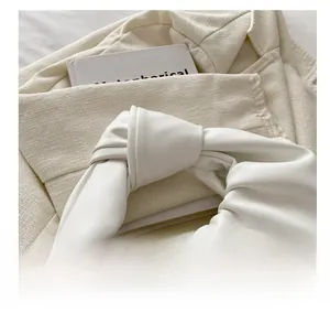 Détail de la poignée nouée sur ce sac à main plissé beige au style minimaliste