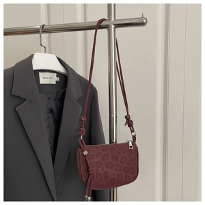 Détail du sac à bandoulière bordeaux à motif léopard avec sangle à nœud élégante