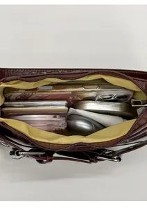 Interior view of spacious dark brown shoulder bag with yellow lining and daily essentials