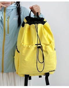 Detail of a yellow drawstring backpack showing the waterproof fabric and brand logo