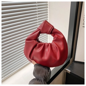 Gros plan sur le cuir plissé rouge foncé et le détail de la poignée nouée du sac à main