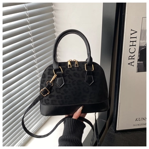 Detail of black leopard print shell bag with golden zippers and leather accents